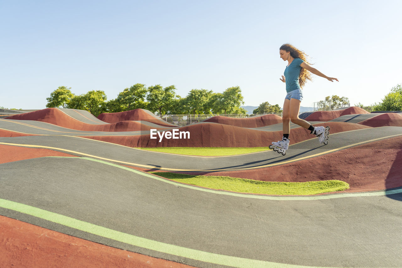 Young woman practicing roller skating on pump track