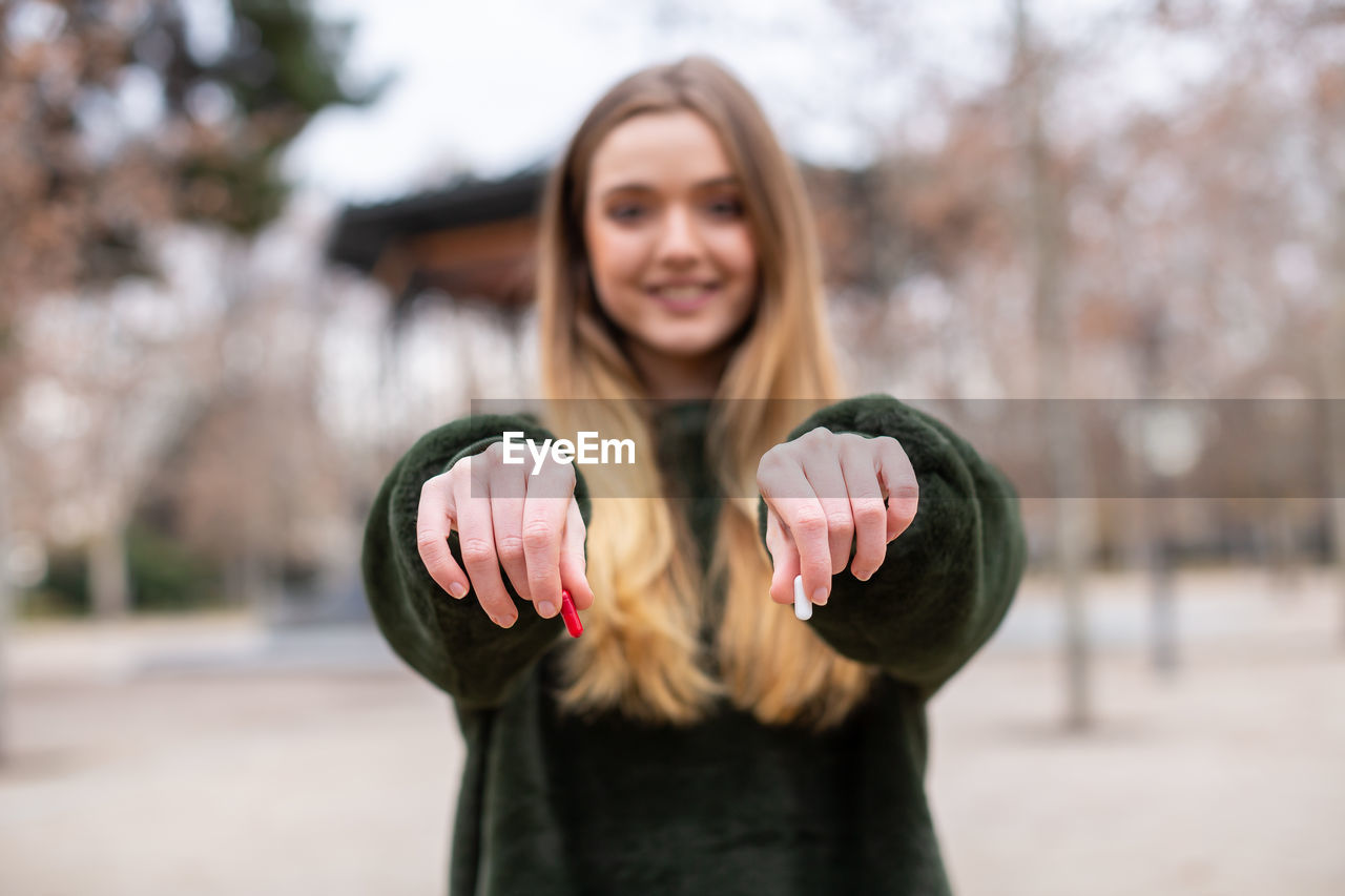 PORTRAIT OF SMILING WOMAN STANDING BY TREE