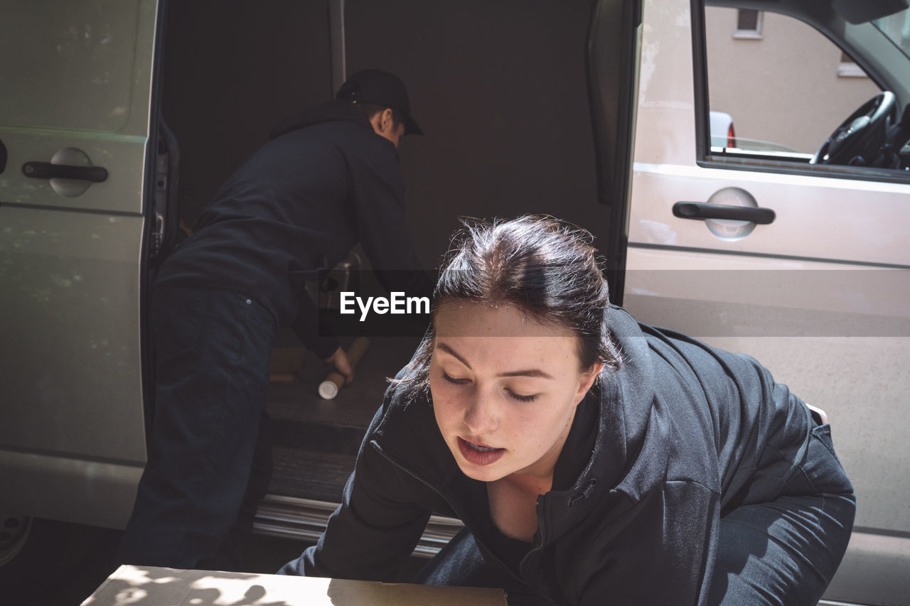 Male and female delivery workers arranging package outside truck