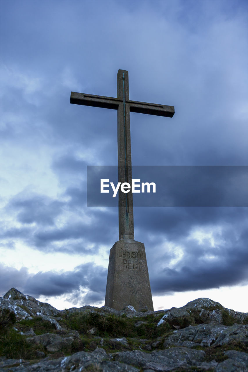 LOW ANGLE VIEW OF CROSS ON ROCK