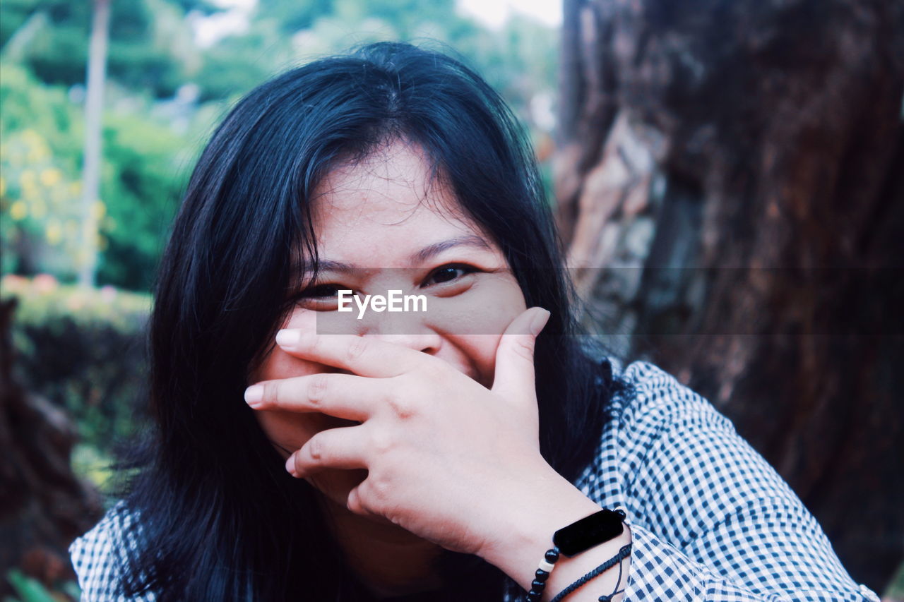 Close-up portrait of young woman with hand covering mouth