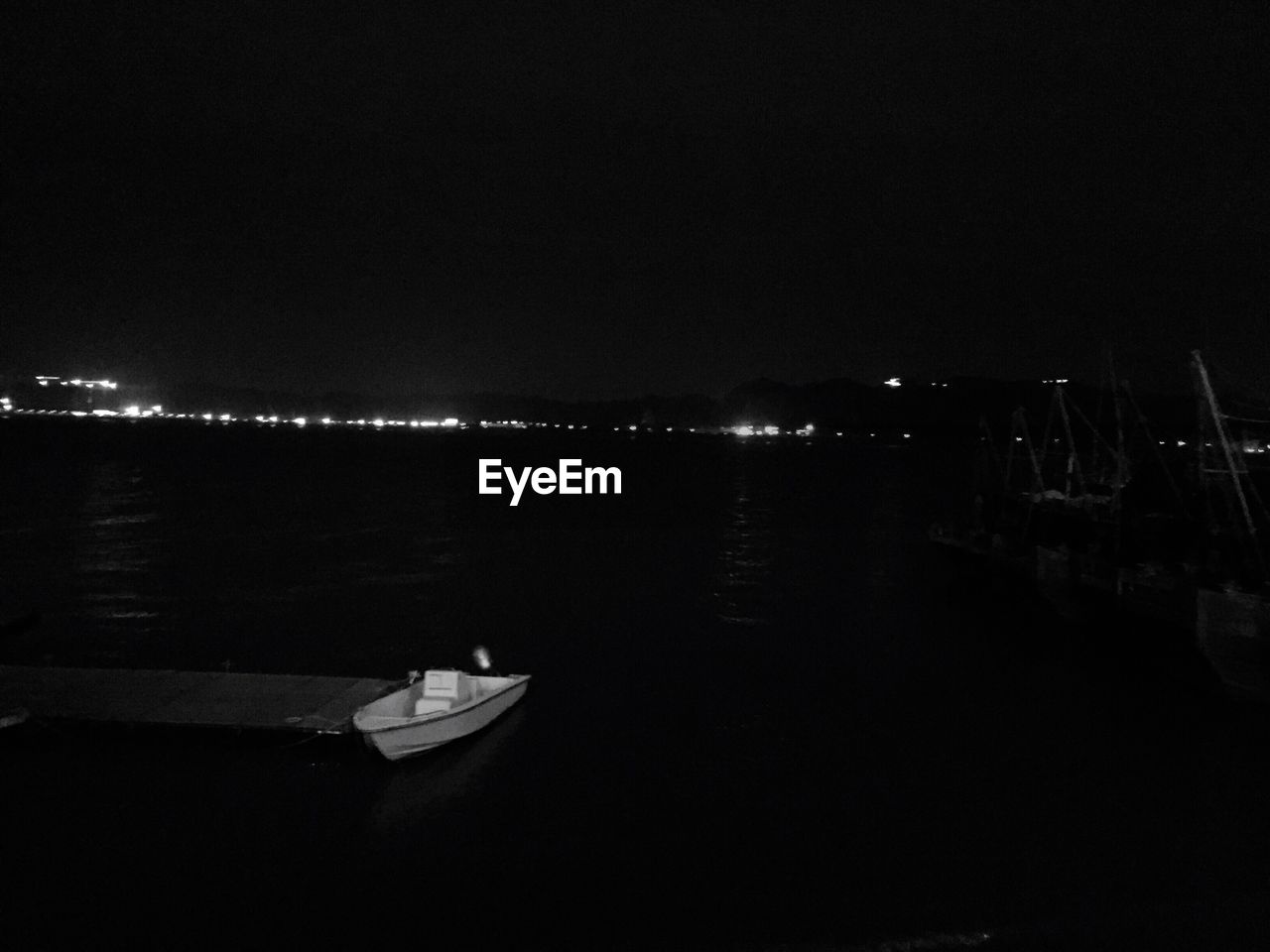 BOATS MOORED IN ILLUMINATED HARBOR AGAINST CLEAR SKY AT NIGHT