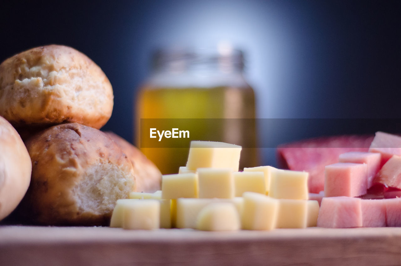 Close-up of cheese by bread and meat with beer jar in background