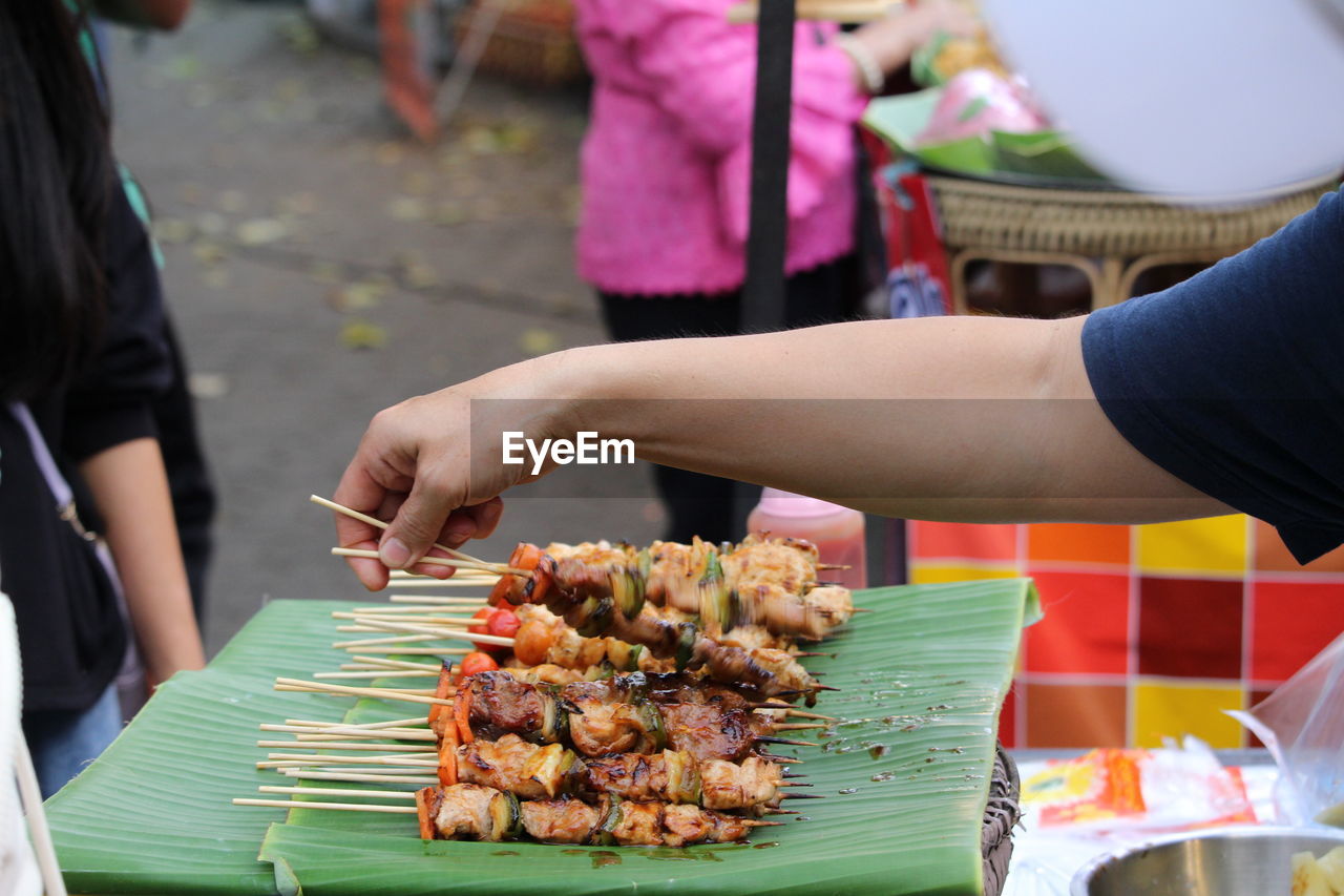 food, food and drink, hand, dish, meal, street food, adult, women, freshness, group of people, satay, market, cuisine, skewer, business, brochette, midsection, meat, holding, fast food, barbecue, healthy eating, day, focus on foreground, outdoors, men, market stall, concession stand, celebration, table, wellbeing, asian food, lifestyles, event, city