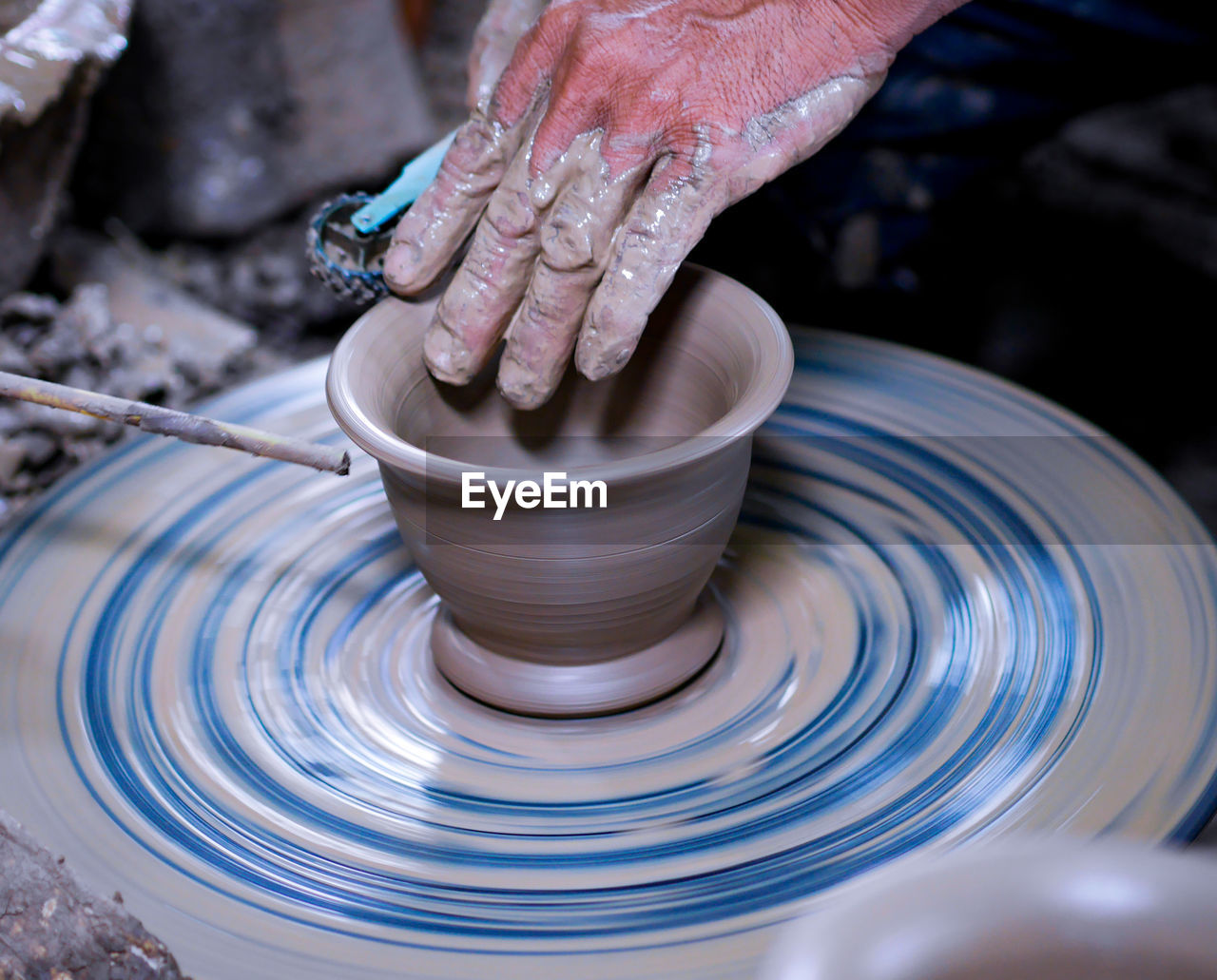 Cropped hands of man molding shape on pottery wheel