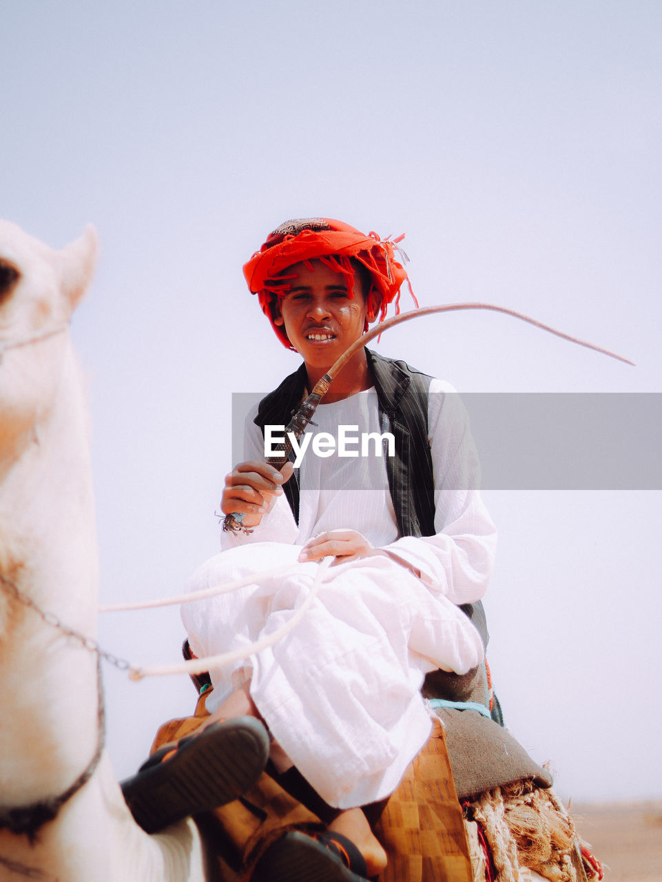 Portrait of bedouin young man on his camel in the desert 