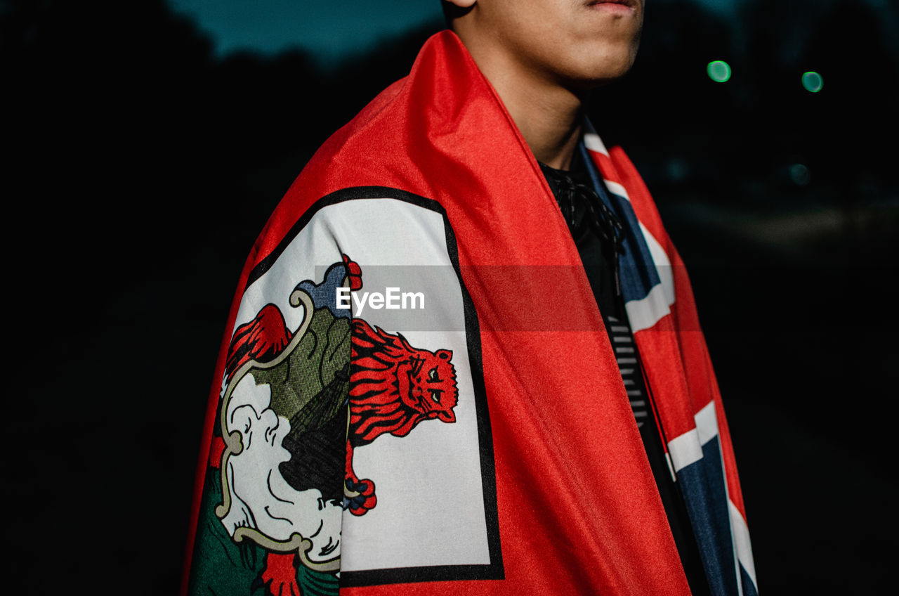 Midsection of boy standing with flag at night