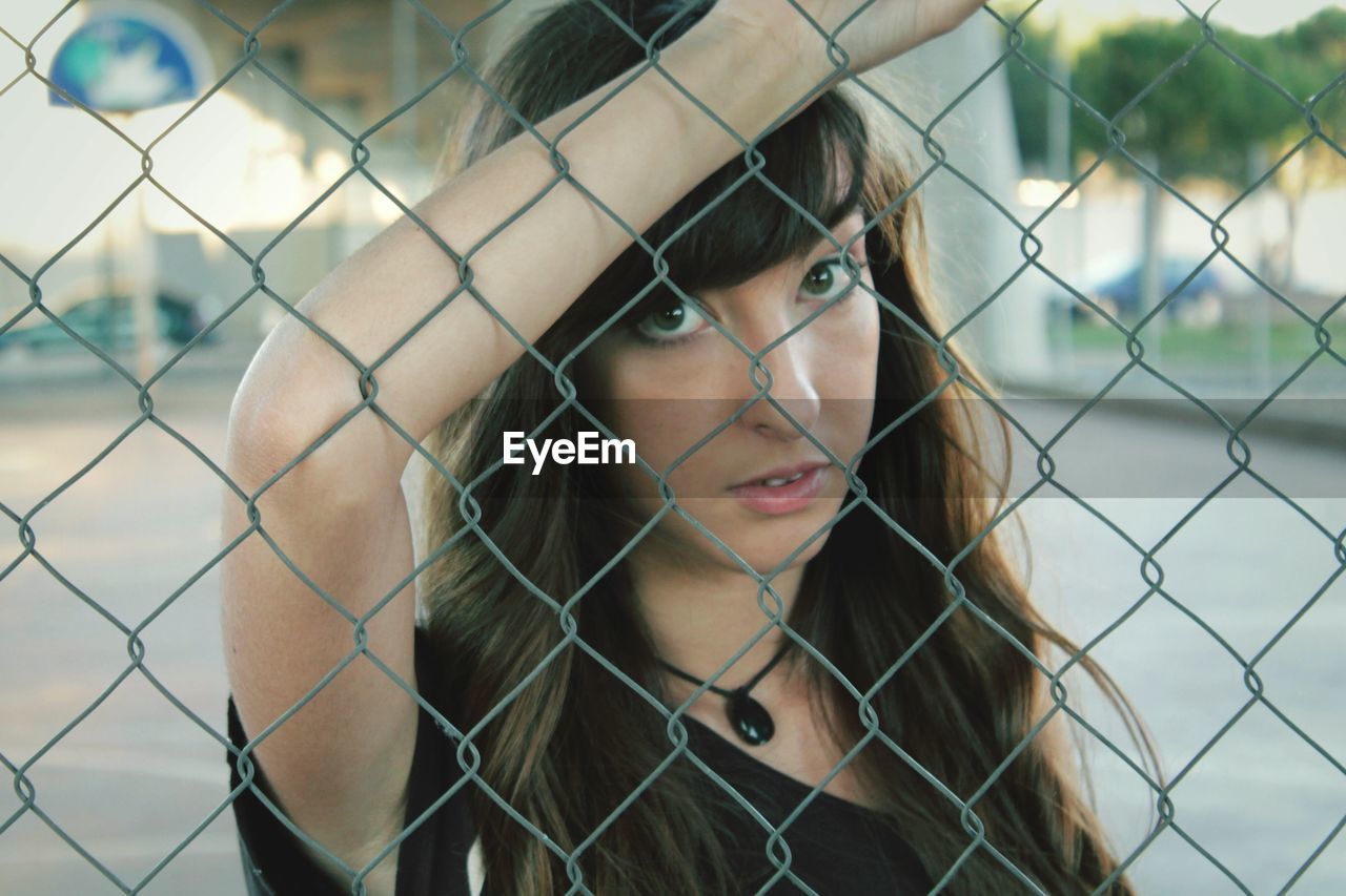 Portrait of woman seen through chainlink fence