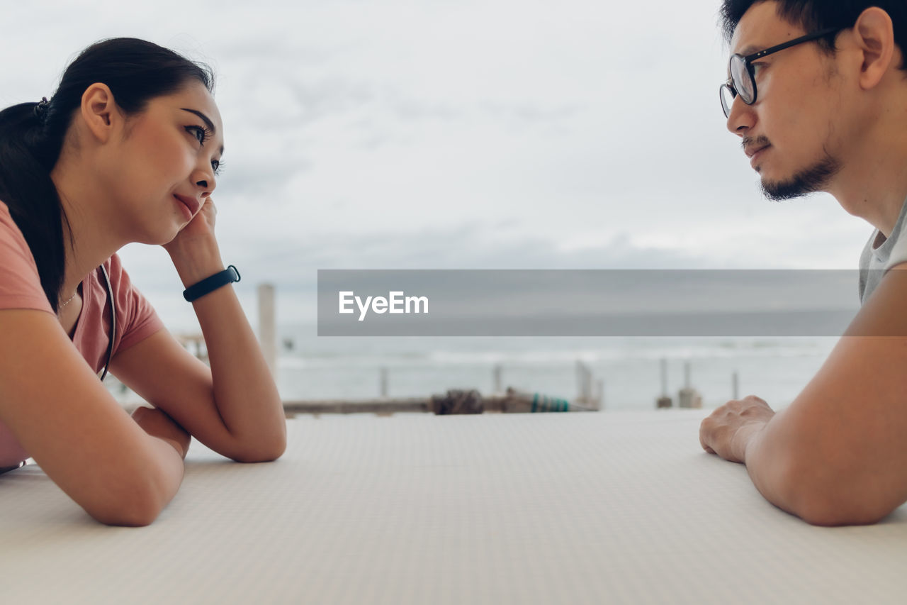 YOUNG WOMAN LOOKING AT SEA AGAINST SKY