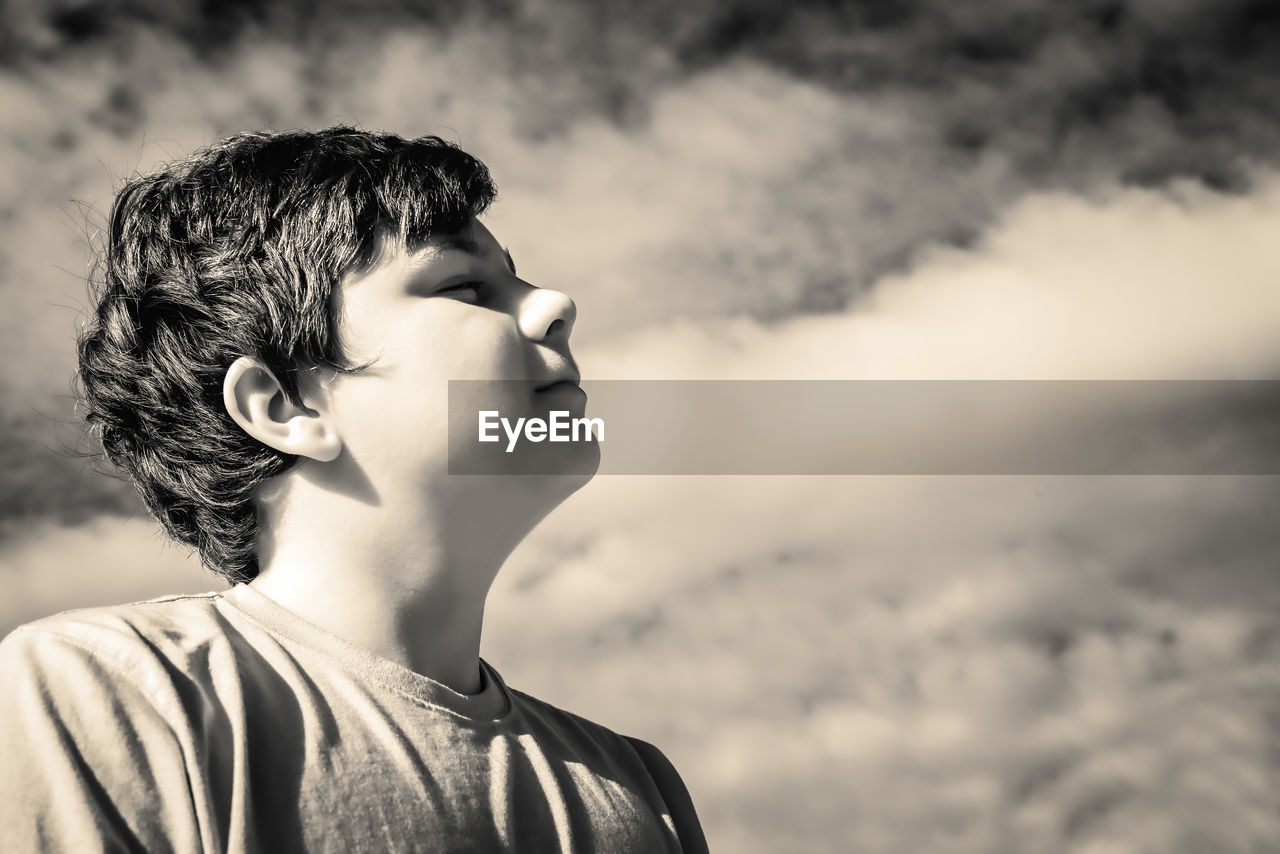 Portrait of boy looking away against sky