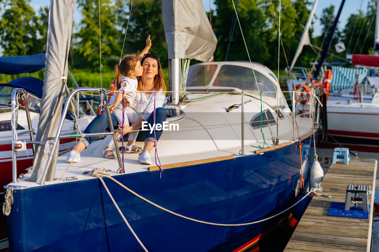 Girl kissing mother sitting on yacht