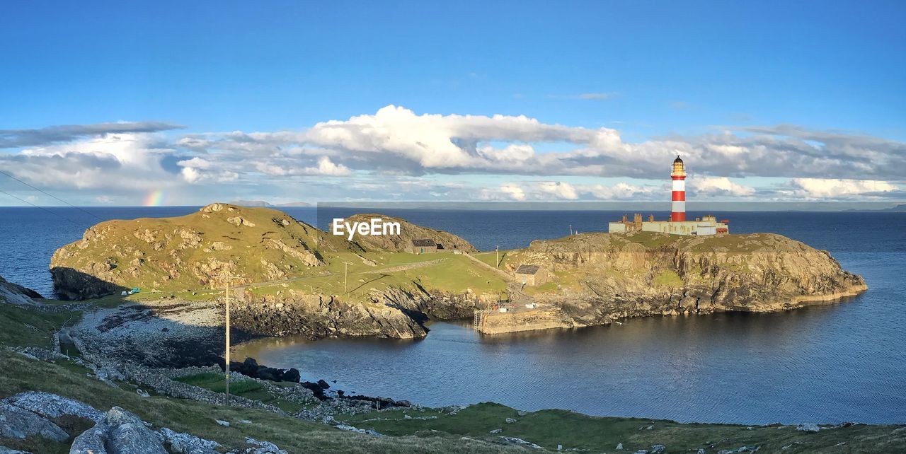 Lighthouse by sea against sky