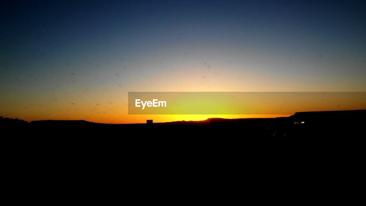 SILHOUETTE LANDSCAPE AGAINST CLEAR SKY DURING SUNRISE