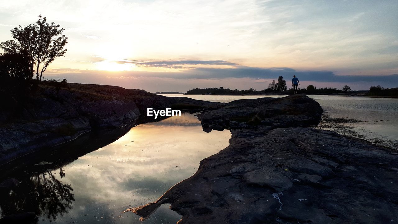 ROCKS ON SHORE AGAINST SKY DURING SUNSET