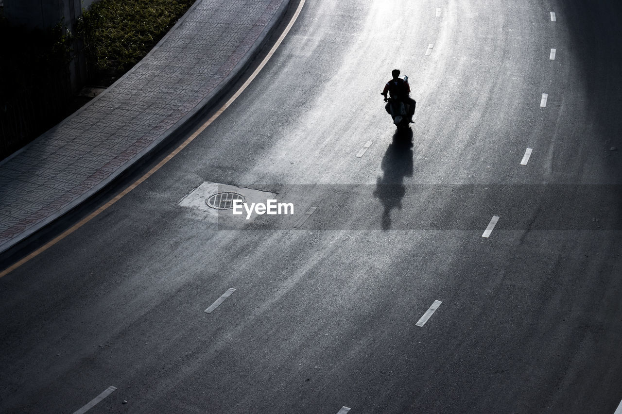 HIGH ANGLE VIEW OF A PERSON WALKING ON ROAD