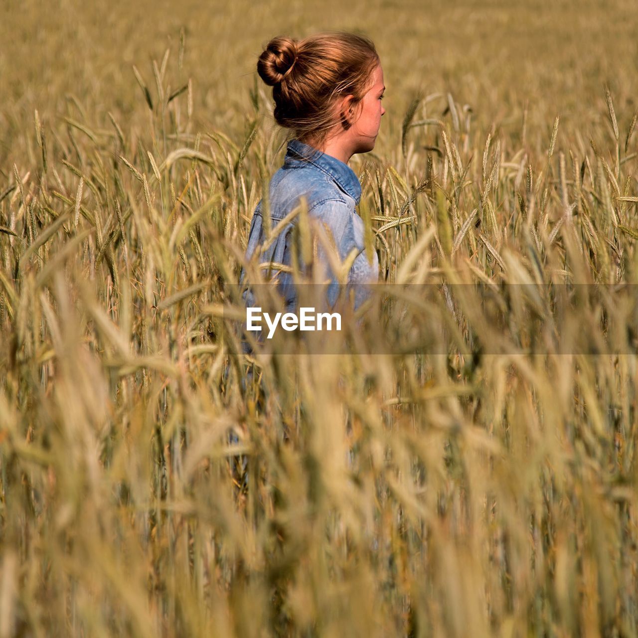 Side view of teenage girl standing amidst plants in farm