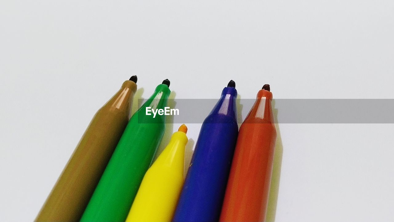 HIGH ANGLE VIEW OF COLORED PENCILS AGAINST WHITE BACKGROUND