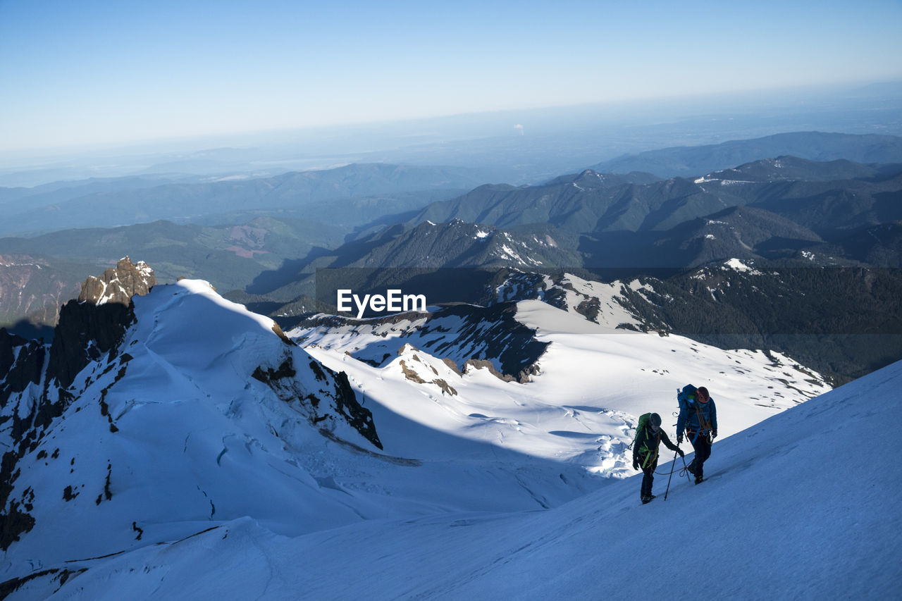 Two athletes hike up a glacier on mt. baker in the shadow of the summit.