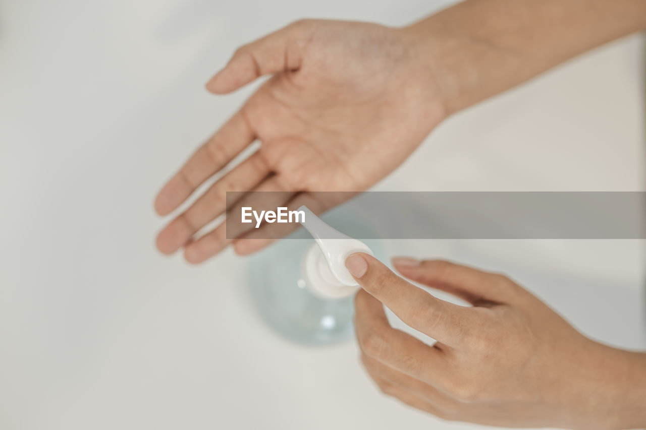 CLOSE-UP OF HAND HOLDING WHITE OVER GRAY BACKGROUND