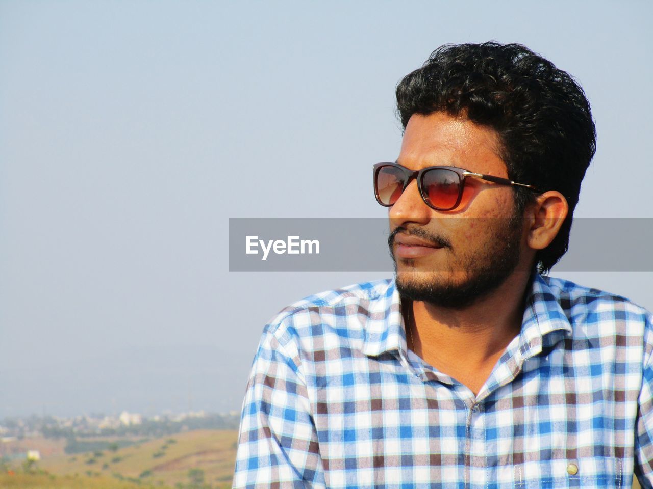 Close-up of smiling young man wearing sunglasses against clear sky