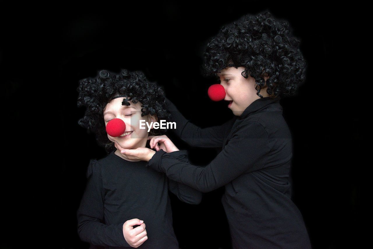 Cute siblings wearing clown against black background