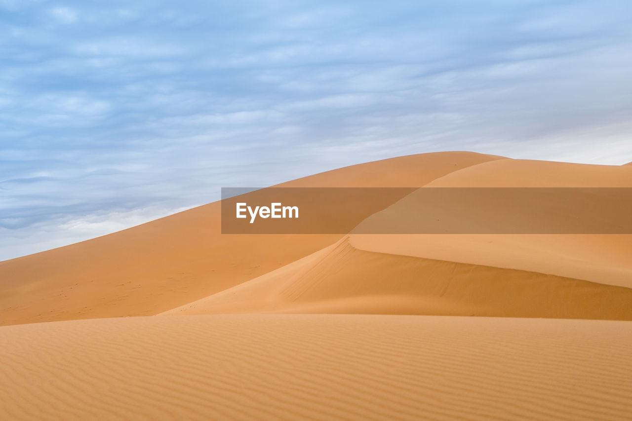 Sand dunes in desert against sky