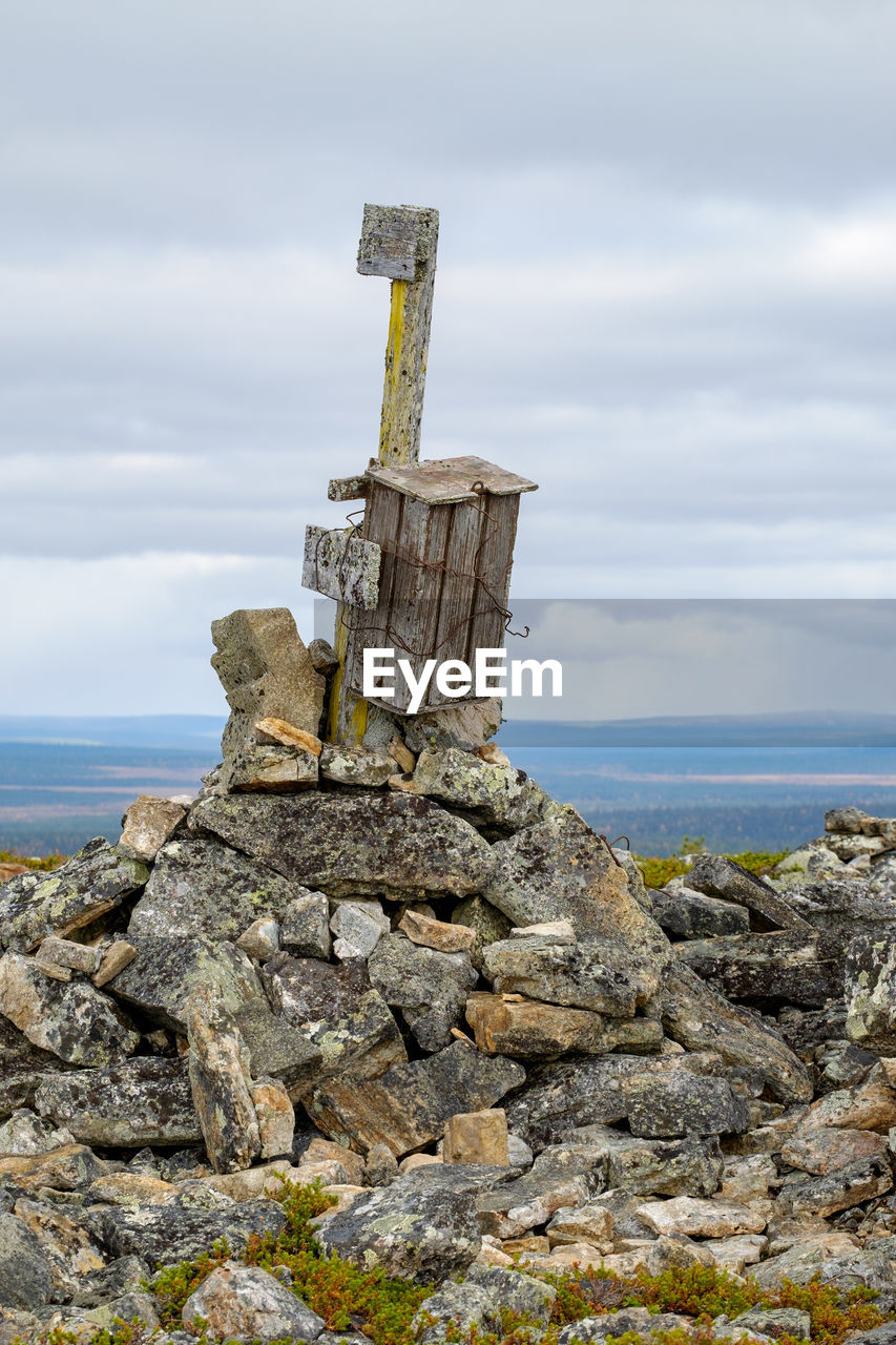 Cross on rock by sea against sky