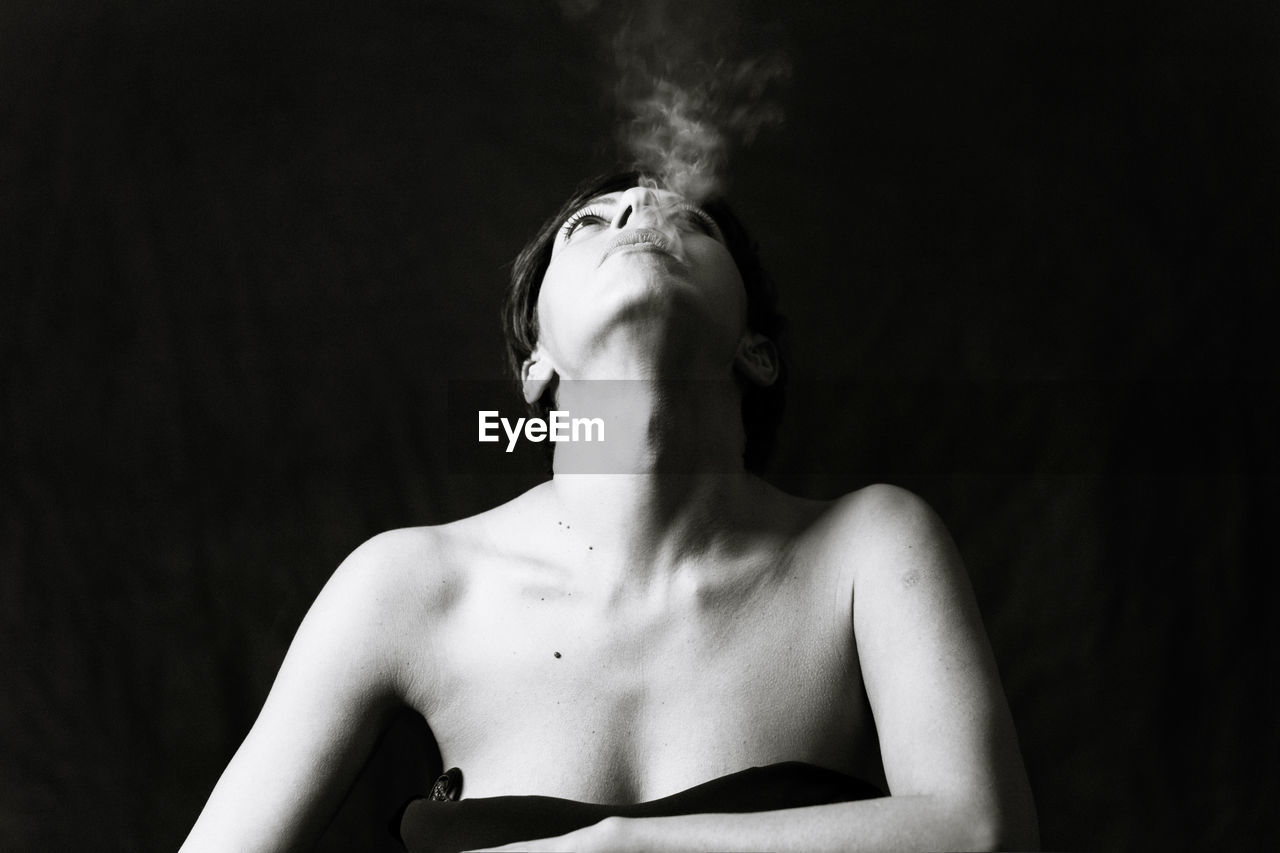 Close-up of woman smoking in darkroom