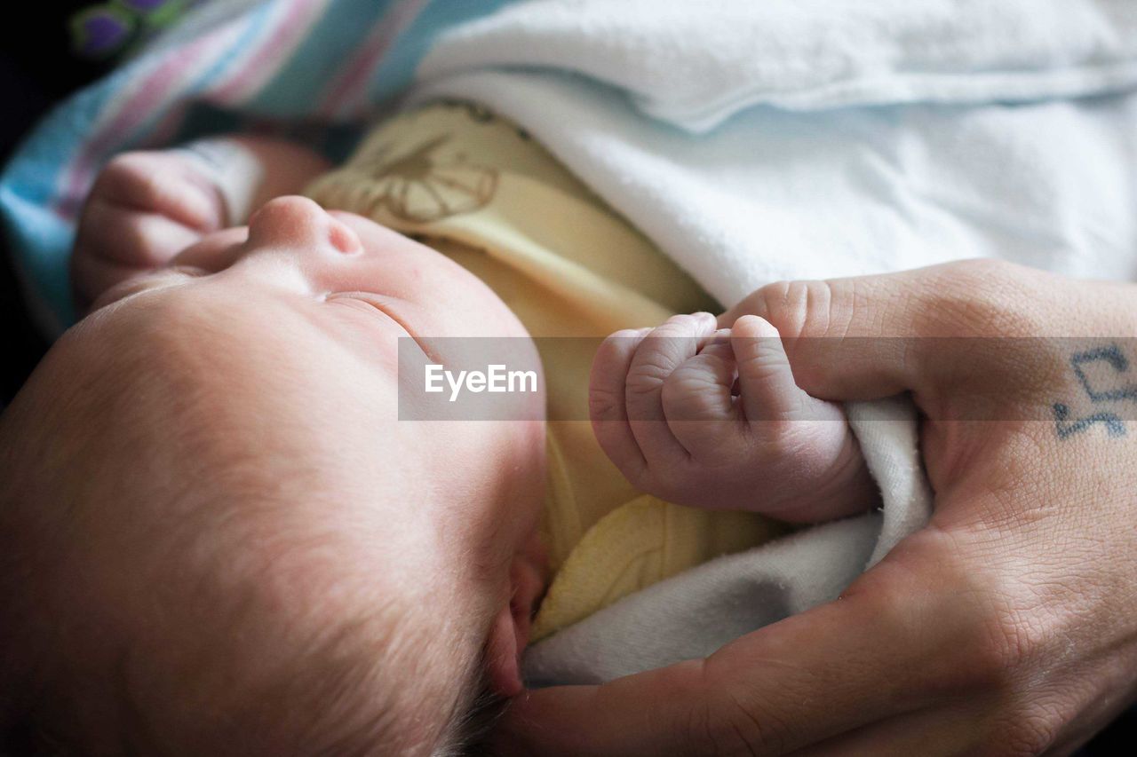 Close-up of baby girl holding father thumb in hospital