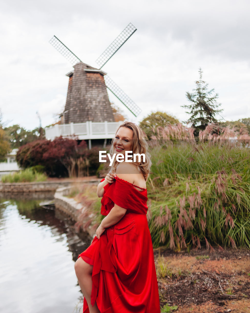 Portrait of smiling young woman standing against windmill