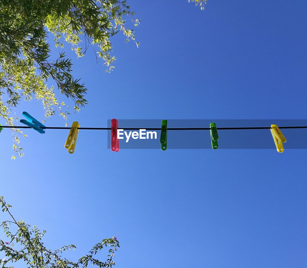 LOW ANGLE VIEW OF MULTI COLORED HANGING AGAINST CLEAR BLUE SKY