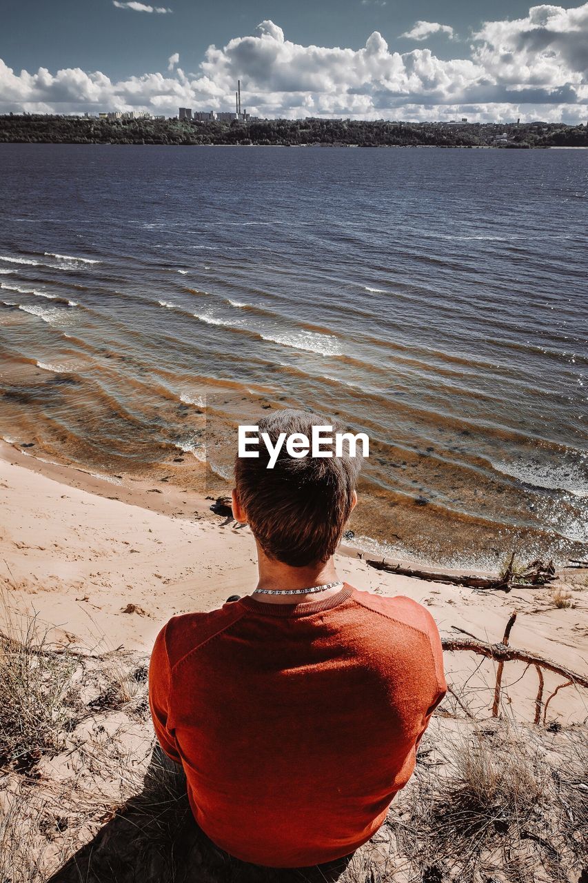 Rear view of man sitting at beach