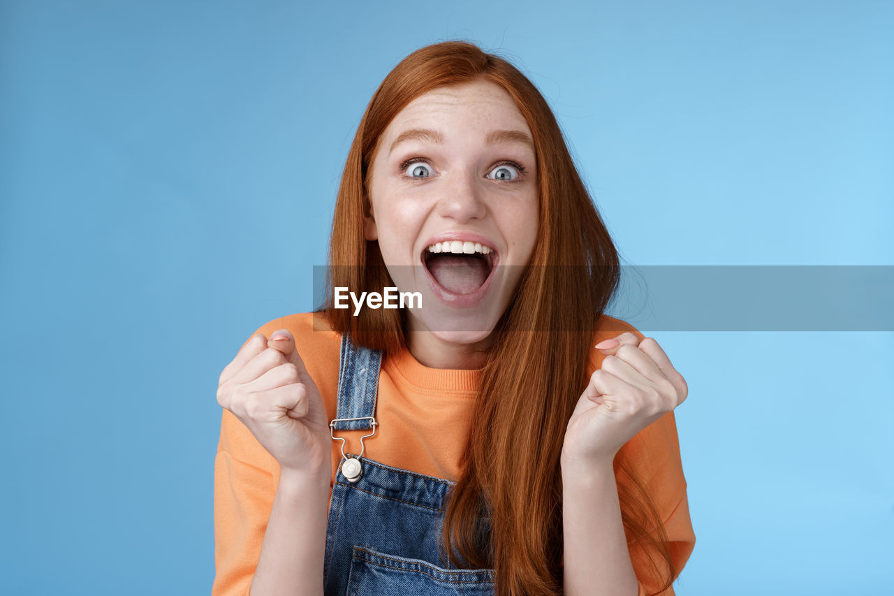 Excited young woman against blue background