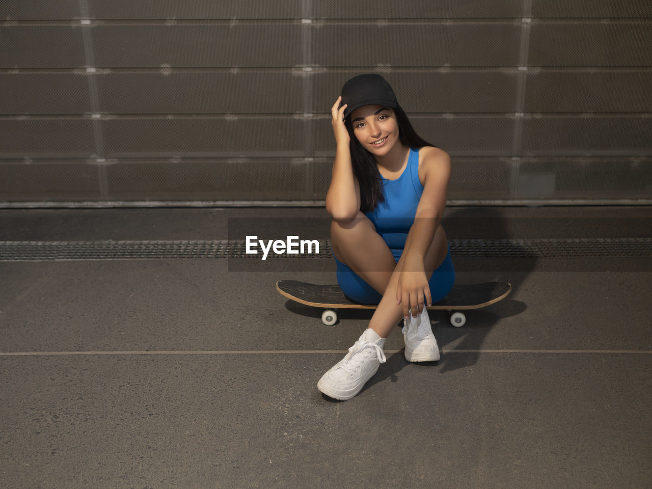 Girl smiles sitting on a skateboard