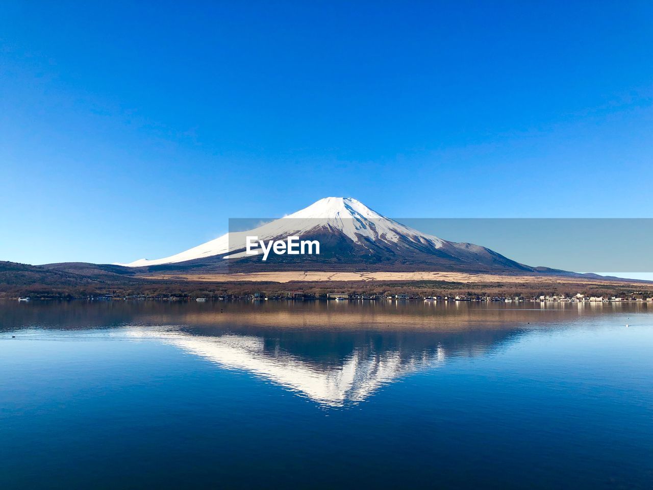 SCENIC VIEW OF LAKE AND SNOWCAPPED MOUNTAINS AGAINST BLUE SKY