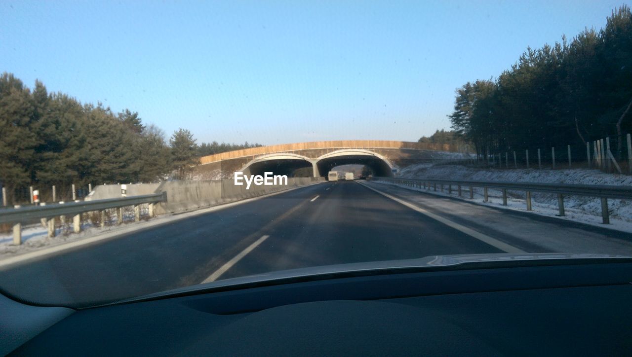 CAR ON ROAD AGAINST CLEAR SKY SEEN THROUGH WINDSHIELD