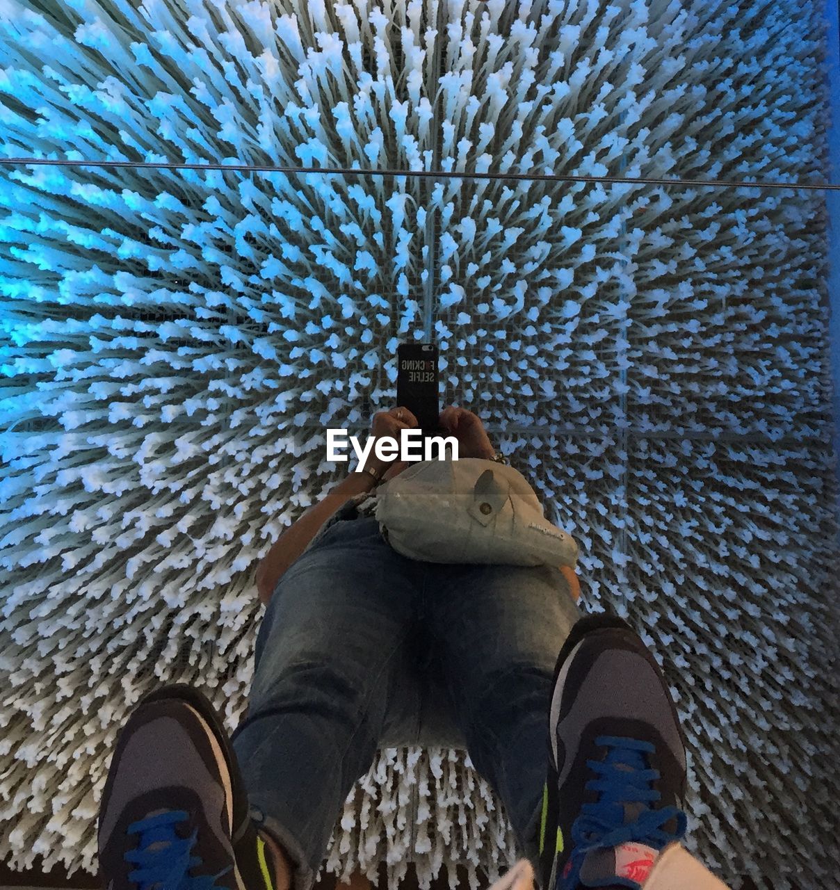Low section of person photographing while standing on glass floor