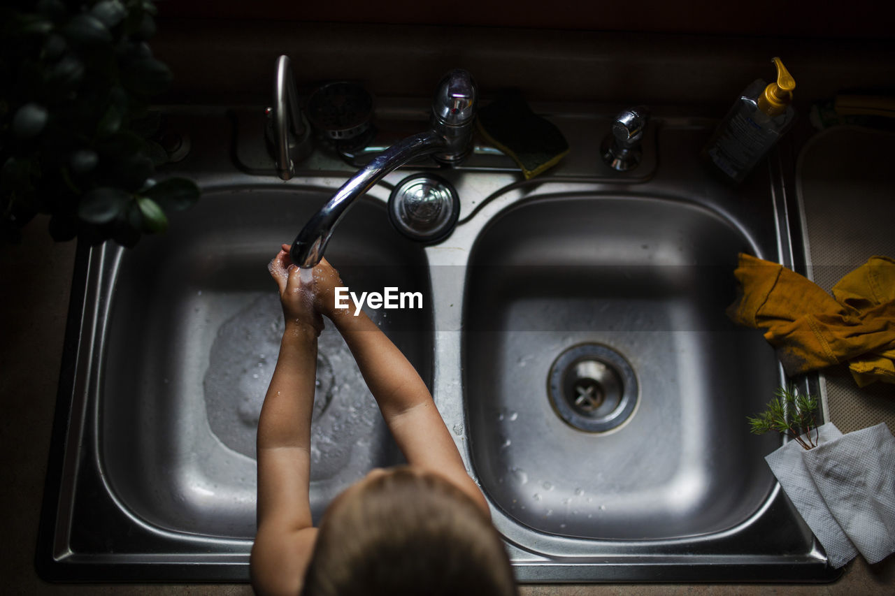 High angle view of boy washing hands in kitchen sink at home