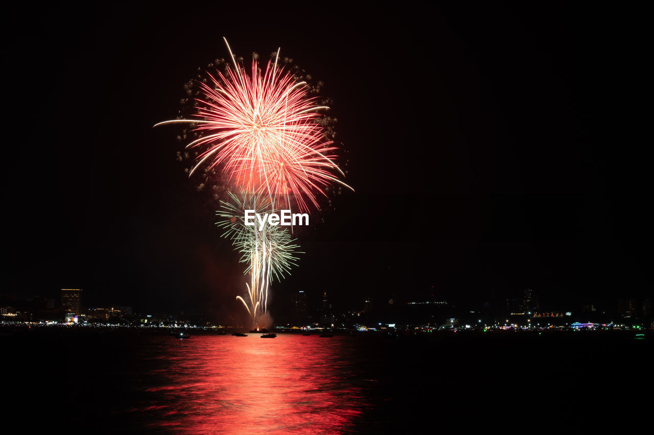 low angle view of firework display over river against sky at night
