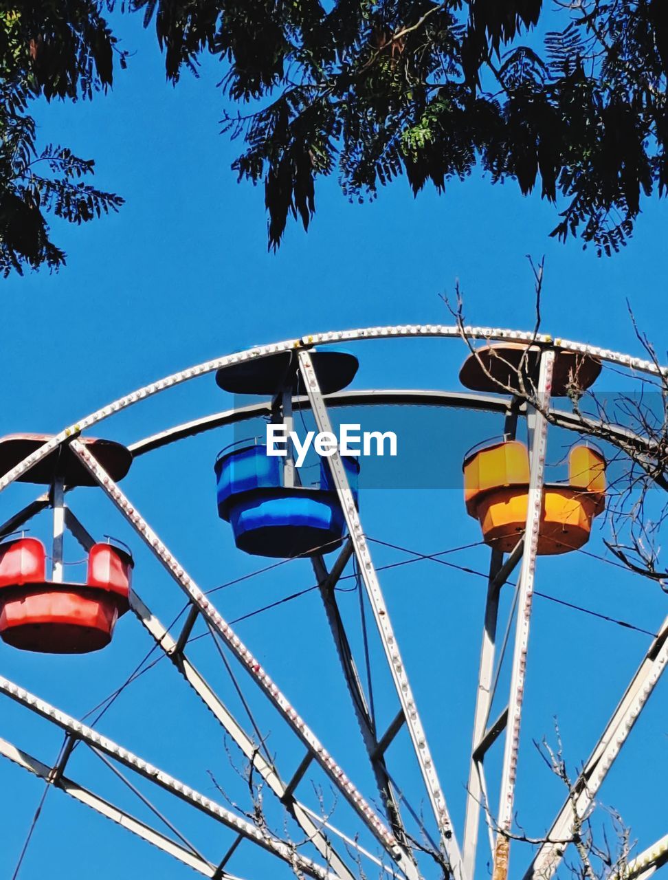 sky, amusement park ride, amusement park, nature, ferris wheel, blue, low angle view, arts culture and entertainment, tree, park, clear sky, day, recreation, no people, outdoors, plant, sunny, fun, leisure activity