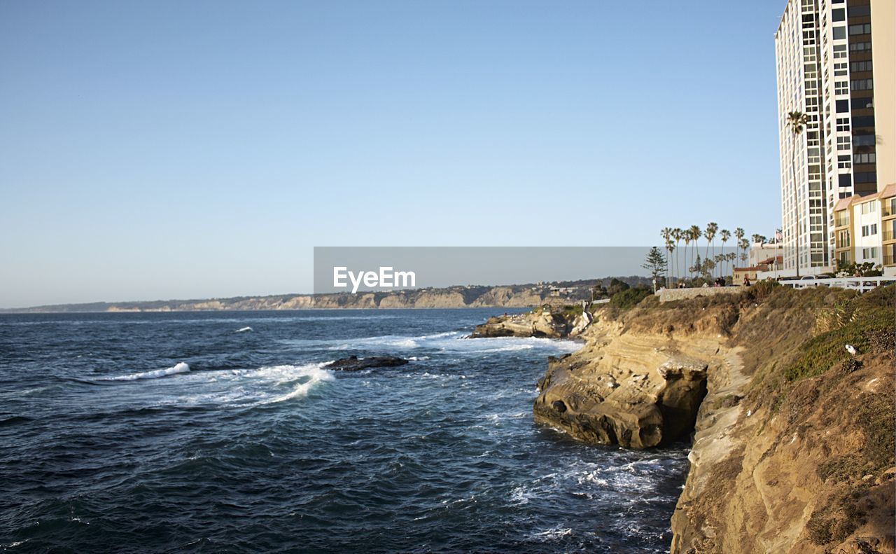 Scenic view of la jolla cove by buildings against clear sky