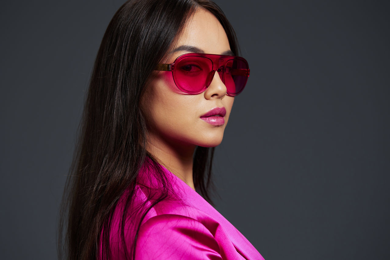 portrait of woman wearing sunglasses against black background