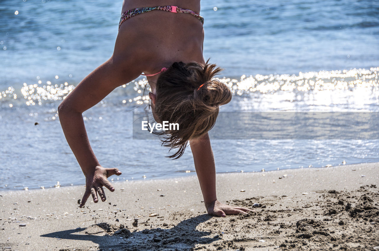 Woman doing handstand on beach