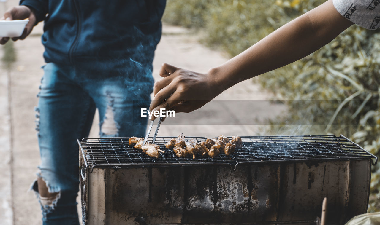 Cropped hand making food on barbecue grill