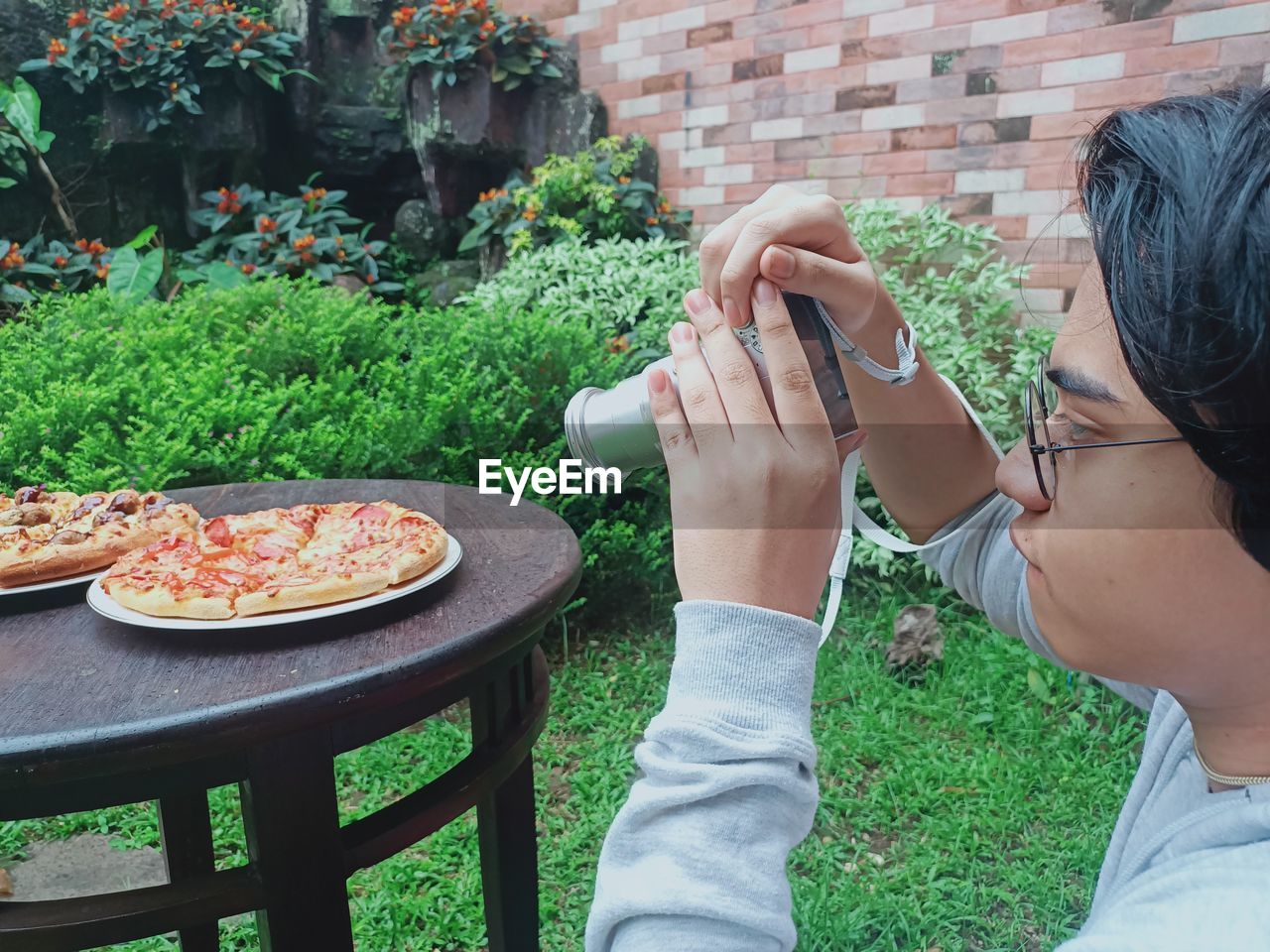 Teenage boy with camera, photographing pizza on the table