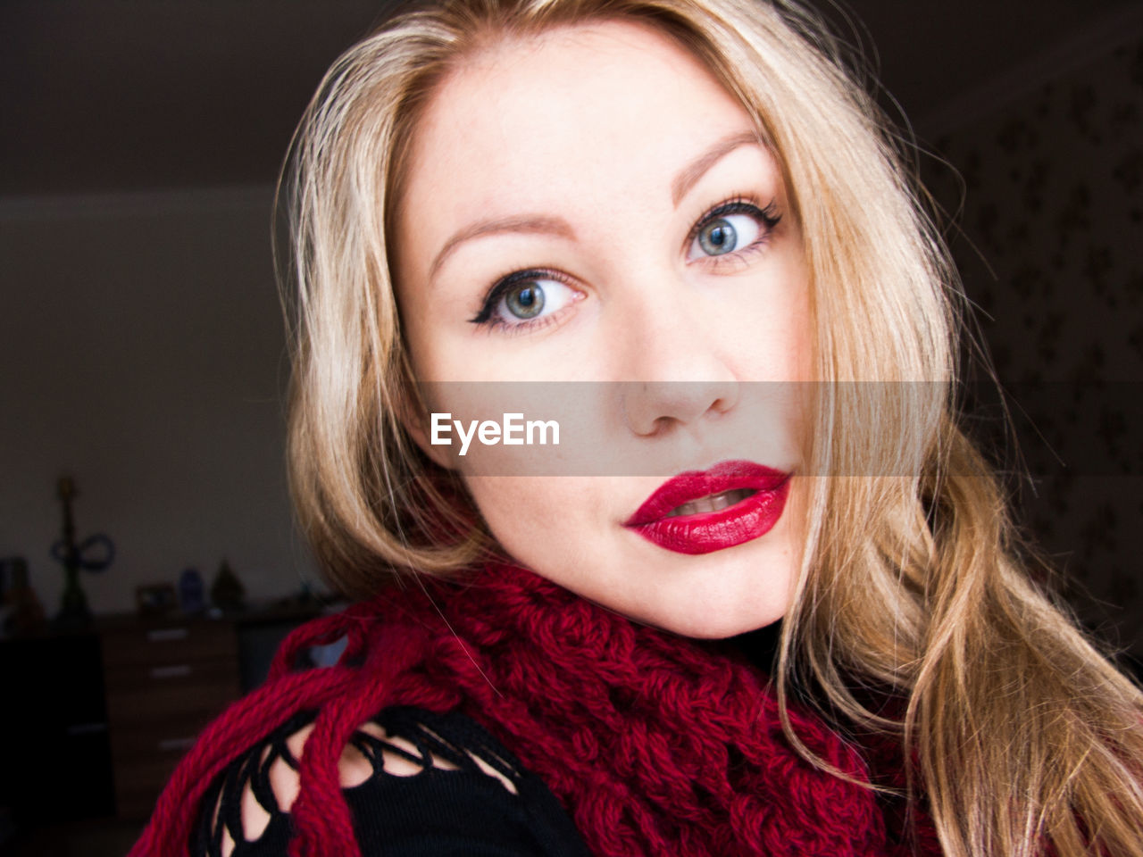 Portrait of beautiful young woman wearing maroon knitted scarf