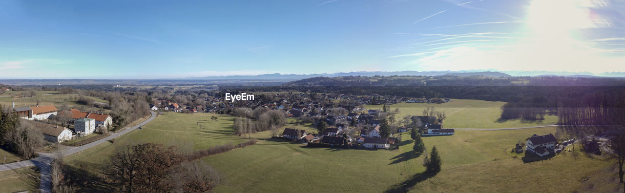 sky, landscape, nature, environment, aerial photography, architecture, scenics - nature, mountain range, sunlight, building, building exterior, built structure, plant, land, mountain, house, panoramic, high angle view, beauty in nature, cloud, residential district, tree, day, city, outdoors, rural scene, field, no people, tranquility, agriculture, sun, village, travel destinations, aerial view, valley, tranquil scene, blue, town, travel, horizon