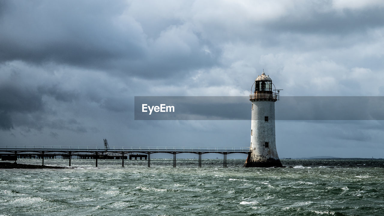 Lighthouse in sea against sky