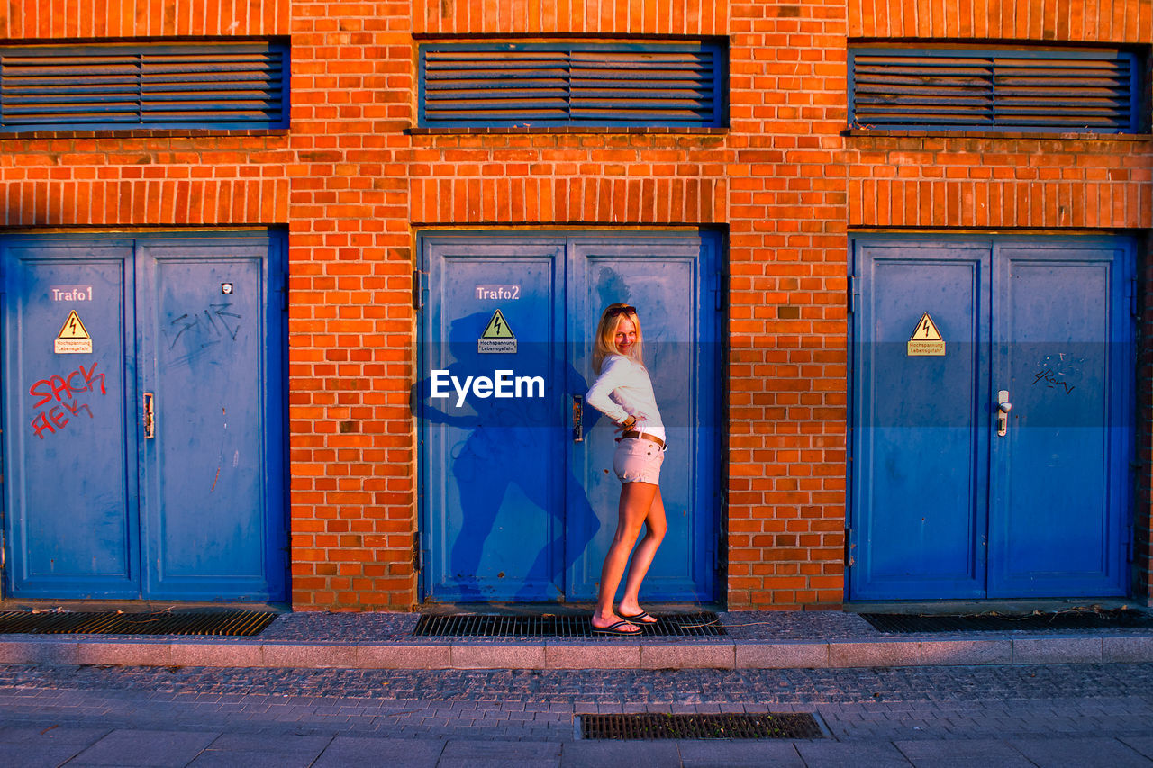 Woman standing against blue door