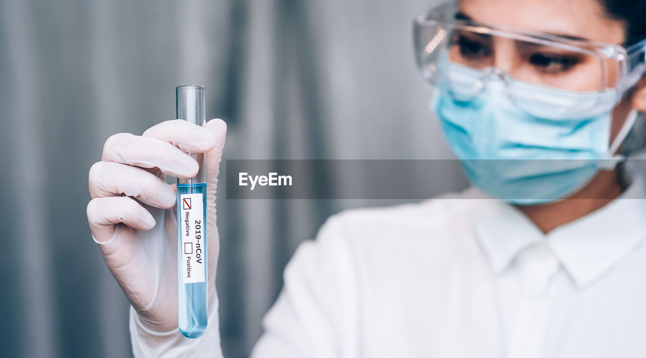 Midsection of scientist holding test tube in laboratory